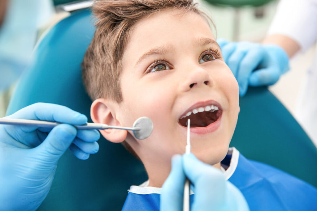 Dentist examining little boy's teeth in clinic