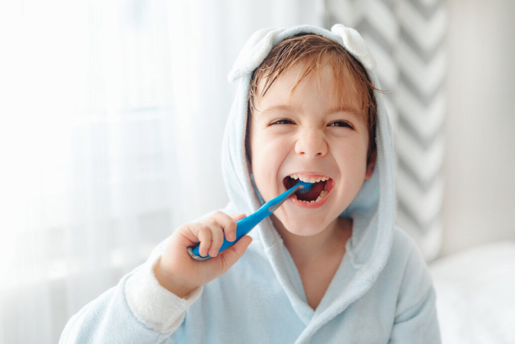 Portrait of smiling happy child brushing teeth with toothbrush. Dental hygiene of little boy, medical care, morning routine.