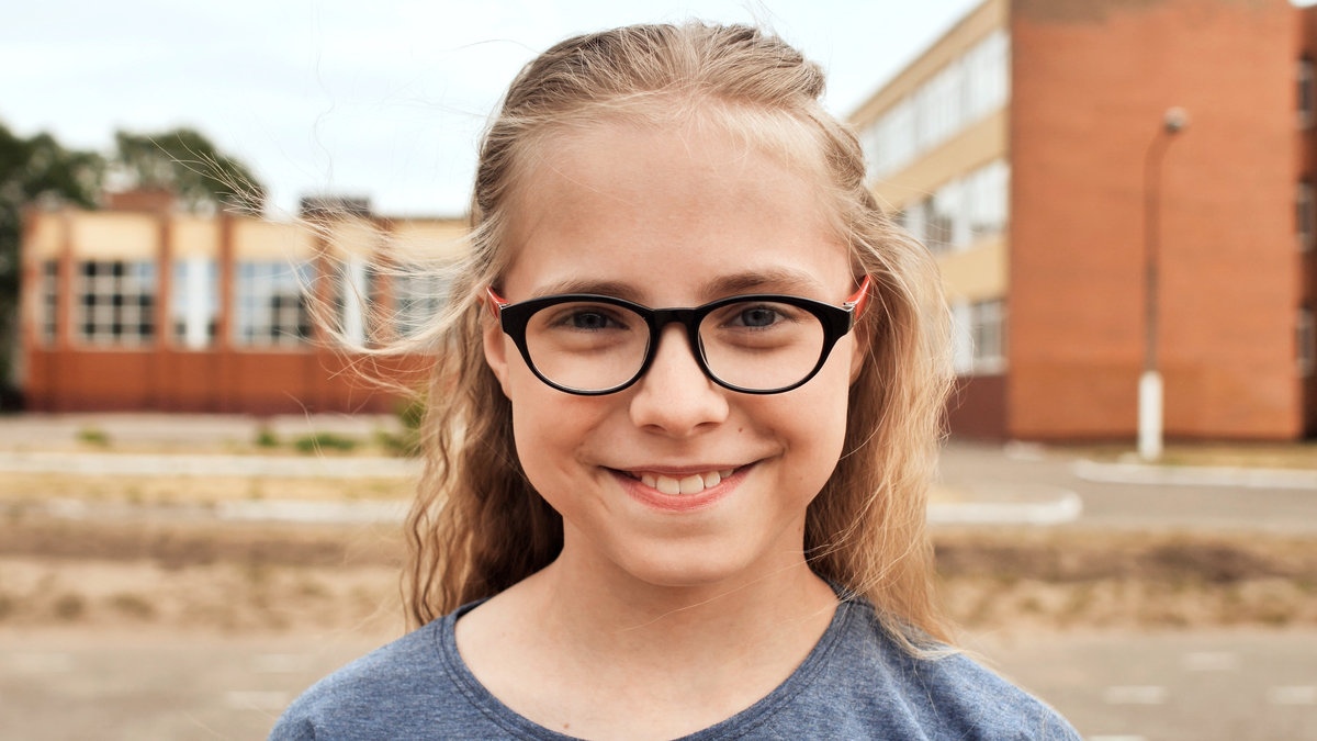 Smiling blonde 11 year old girl with glasses. Face close-up