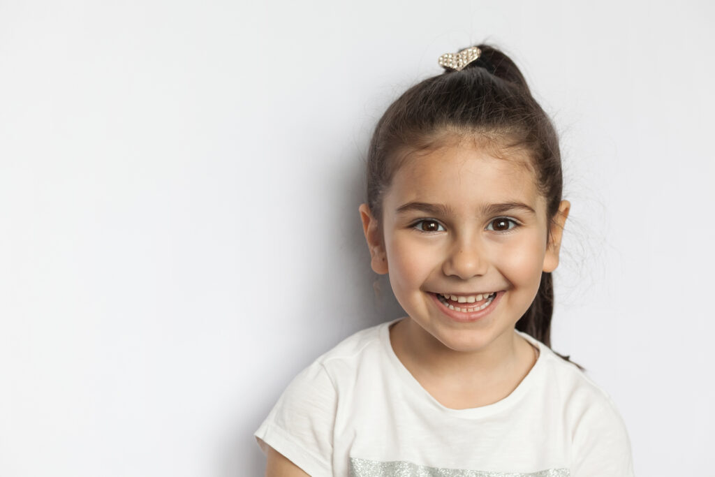 Portrait of happy cute brunette child girl on white background