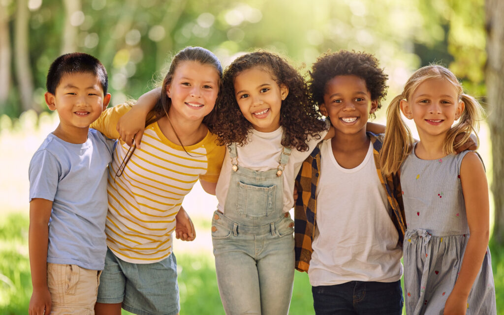 Portrait, friends and children standing in a line together outdoor, feeling happy while having fun or playing. Diversity, school and smile with kids in a row, posing arm around outdoor in a park.