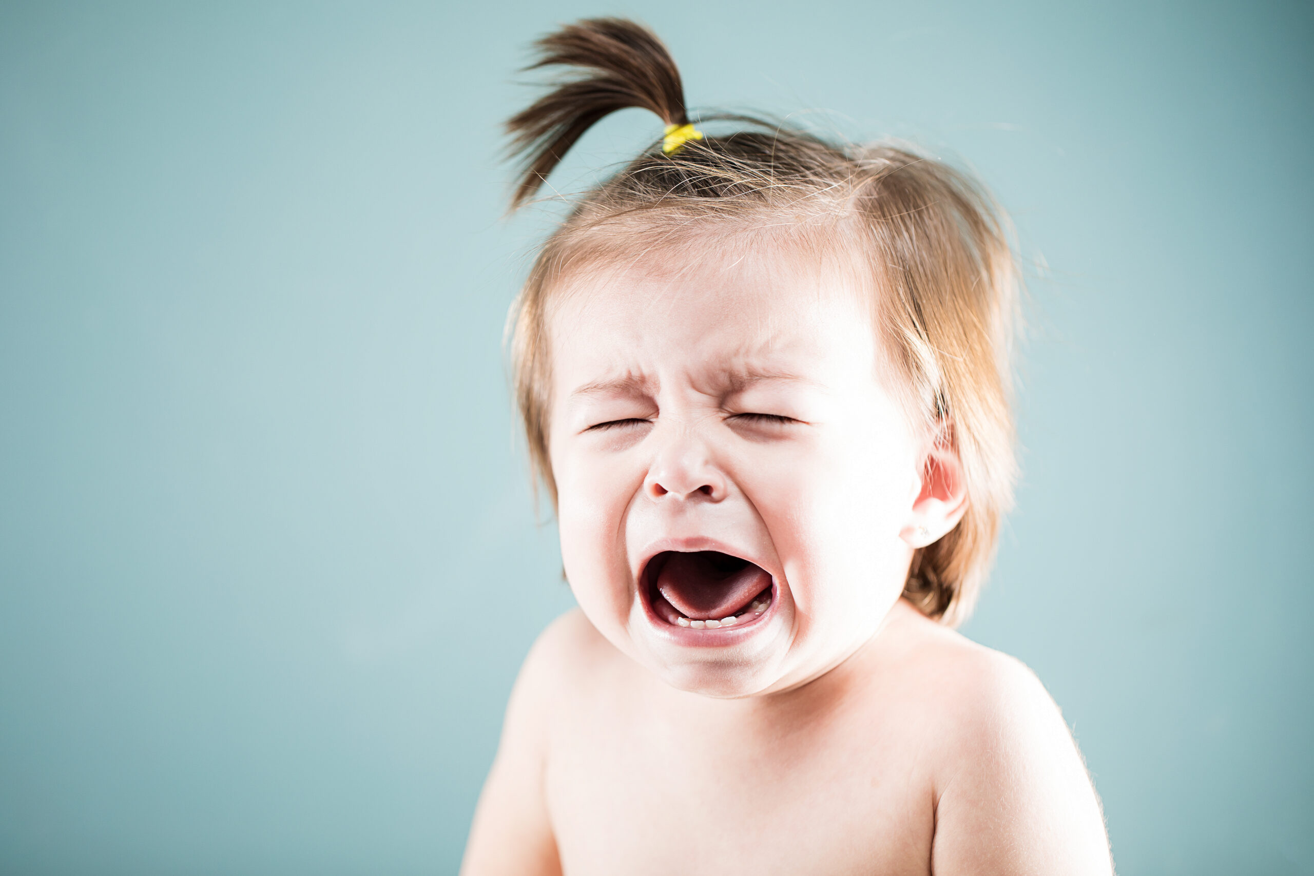 Miserable baby girl crying and looking very upset in a studio