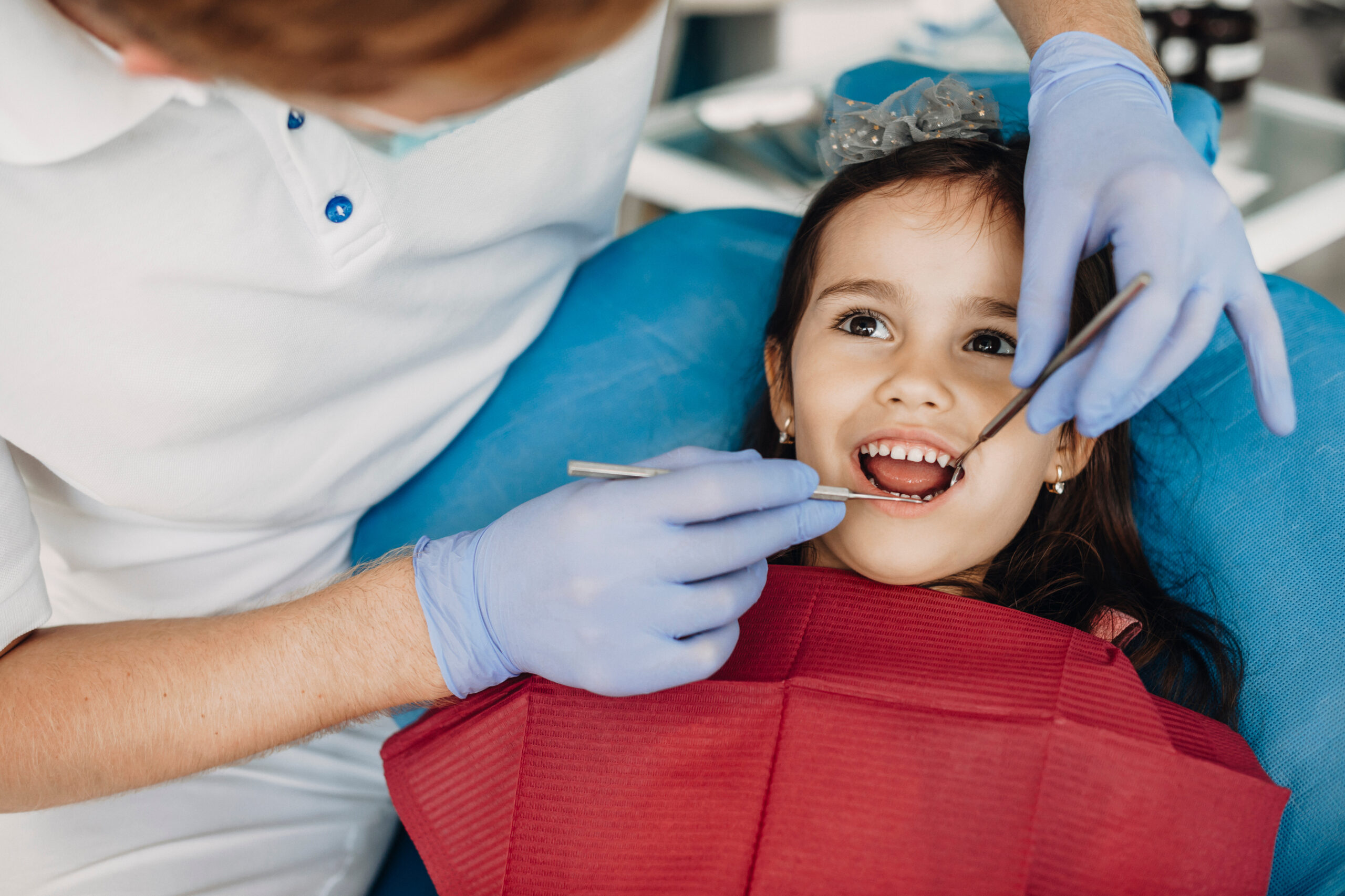Pediatric dentist examining a young child's baby teeth