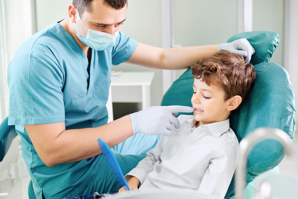 Dentist checking a young boy's teeth in the mirror