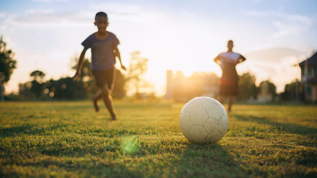 Kids playing soccer outdoors during summer sports