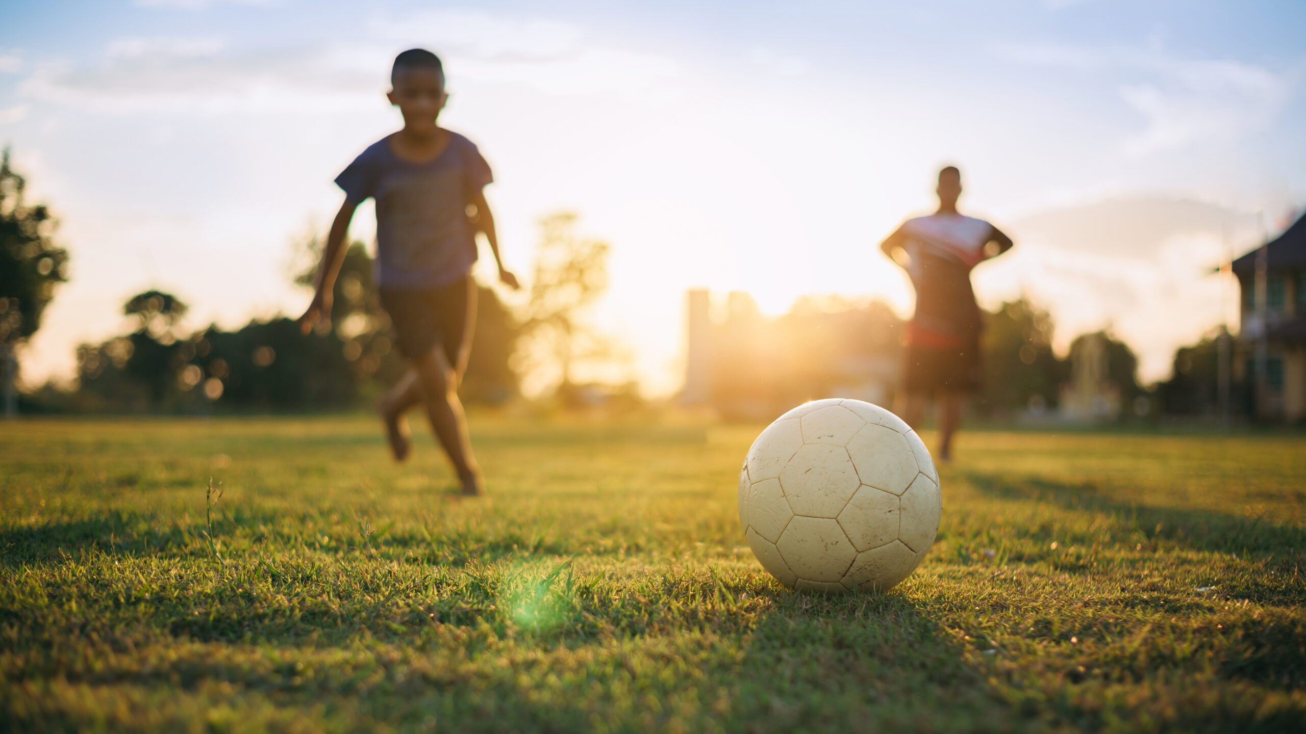 Kids playing soccer outdoors during summer sports