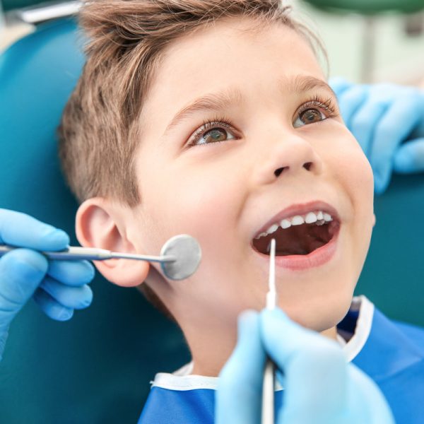 Dentist examining little boy's teeth in clinic