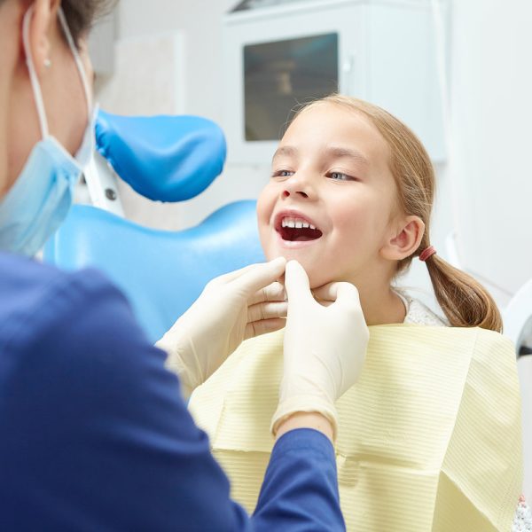 A little child in the examination at the dentist. Observation of teeth of young patient. A sweet five year old girl opens her mouth in the doctor's office.