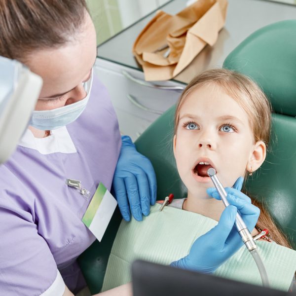 Child to the dentist. Child in the dental chair dental treatment during surgery. Small patient visiting specialist in dental clinic.