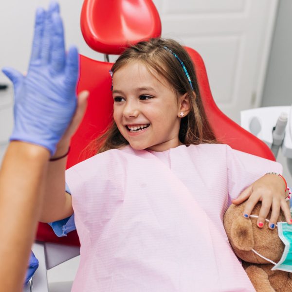 Cute little girl sitting on dental chair and having dental treatment.