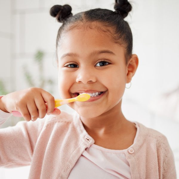 Child, toothbrush and brushing teeth in a home bathroom for dental health and wellness with smile. Face portrait of african girl kid cleaning mouth with a brush for morning routine and oral self care.