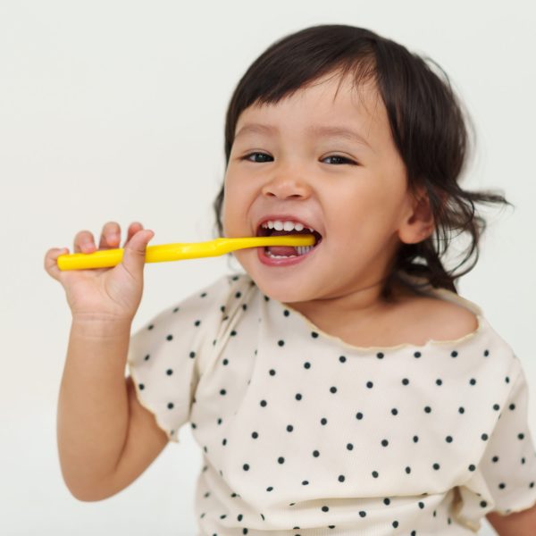 happy toddler girl brushes her teeth with a smile
